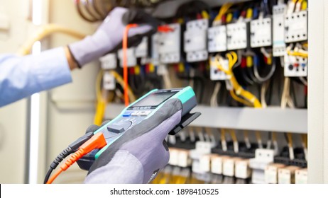 Electrical engineer using digital multi-meter measuring equipment to checking electric current voltage at circuit breaker and cable wiring system in main power distribution board. - Shutterstock ID 1898410525