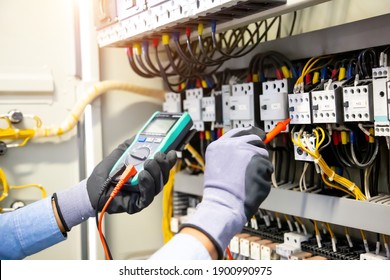 Electrical engineer using digital multi-meter measuring equipment to checking electric current voltage at circuit breaker and cable wiring system in main power distribution board. - Shutterstock ID 1900990975