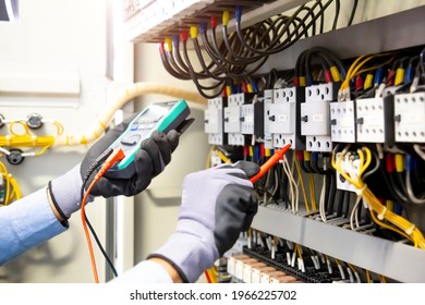 Electrical engineer using digital multi  meter measuring equipment to checking electric current voltage at circuit breaker   cable wiring system in main power distribution board 