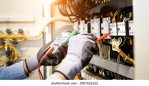 Electrical engineer using digital multi-meter measuring equipment to checking electric current voltage at circuit breaker and cable wiring system in main power distribution board. - Shutterstock ID 2007626162