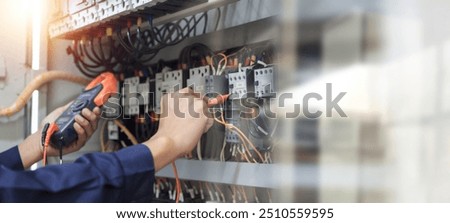 Electrical engineer using measuring equipment to checking electric current voltage at circuit breaker and cable wiring system , Electrical service concept .	
