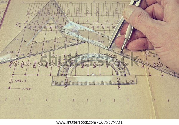Electrical engineer workplace - electrotechnical\
project, rulers, and divider compass. Construction and\
electrotechnology concept. Engineering tools. Circuit diagram on\
background. Retro\
haze