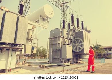 Electrical engineers inspect power transformers in power stations. High pressure using a tablet device.