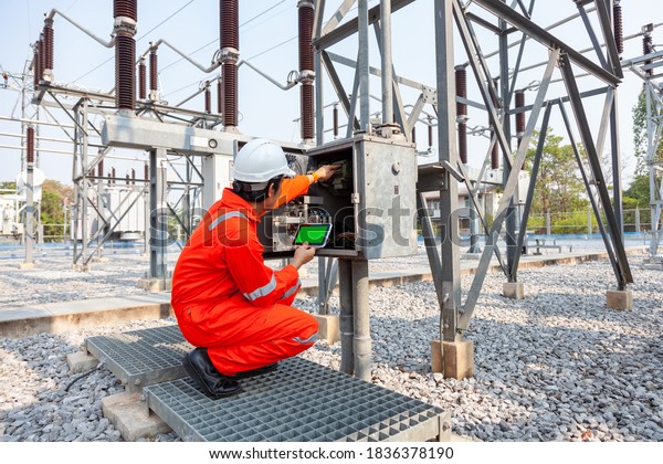 Electrical engineers\
inspect the electrical systems at the equipment control cabinet\
using data from the\
tablet