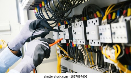Electrical engineers test electrical installations and wiring on protective relays, measuring them with a multimeter.