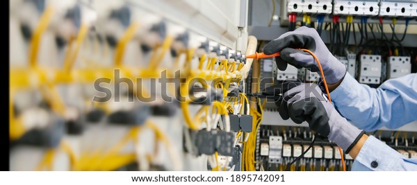 Electrical\
engineers test electrical installations and wiring on protective\
relays, measuring them with a\
multimeter.