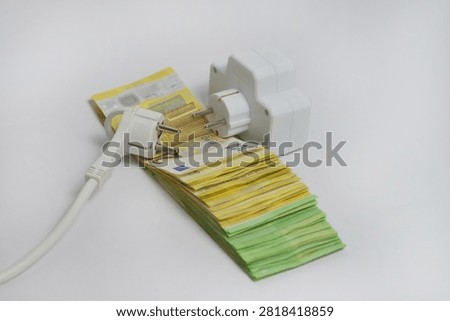 Electrical extension socket and power plug placed on euro banknotes, illustrating rising electricity prices, increasing energy costs, utility bills, inflation and household expenses in Europe.
