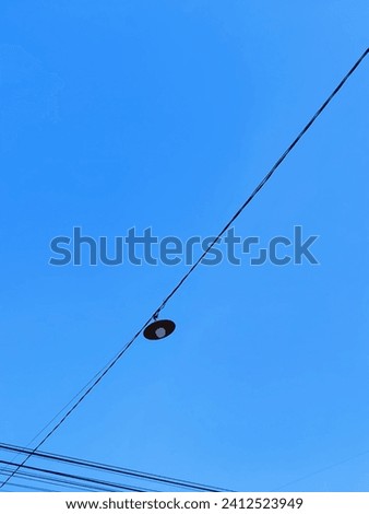 The electrical hanging street lamp connecting cables crisscrossing above look beautiful against the backdrop of the clear bright blue sky. Negative space. Concept of difference.