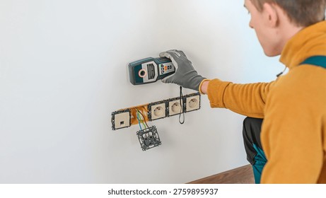 Electrical installation. The electrician's hand using a wall scanner for checking electrical wires in the wall. Metal detector.