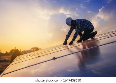 Electrical and instrument technician use wrench to fix and maintenance electric system at solar panel field with sunset sky reflection