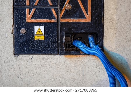 Electrical junction box in building facade with blue conduit urban technical infrastructure detail