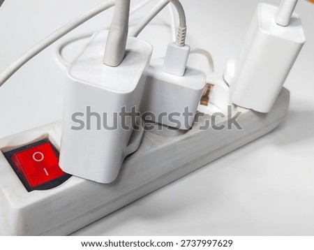 An electrical outlet with multiple chargers connected to it for smartphones.