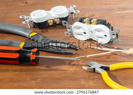 Electrical outlet, screwdriver and wire stripper tools on white background