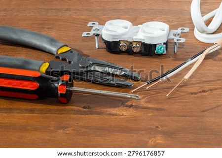 Electrical outlet, screwdriver and wire stripper tools on white background