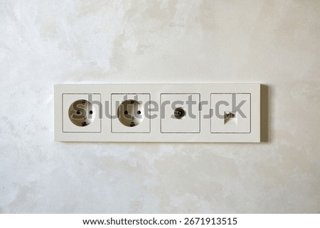 Electrical outlets and a network socket are neatly arranged on a light wall panel in a modern interior. Ideal for home or office.