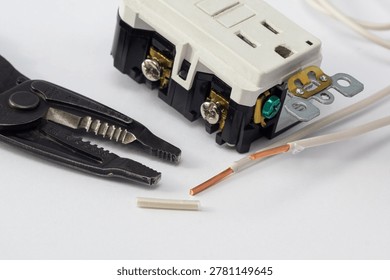 Electrical outlets, screwdriver, and wire stripper tools on a white background, illustrating electrical installation, and DIY projects.