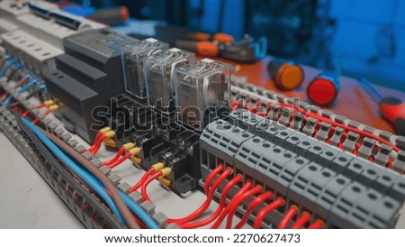 Electrical panel with many red and blue wires, electrical parts, automatic switches, breakers, residual current devices. Close up of a electrical switch on a table in an electrical workshop.