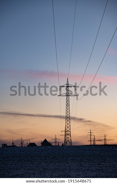 Electrical Pylons and cables silhouetted on evening sky\
in the countryside 