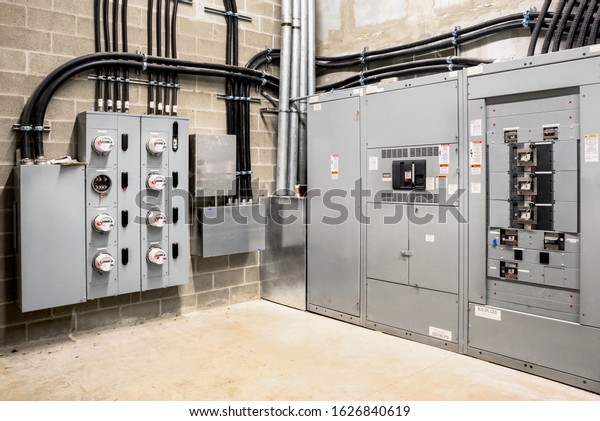 Electrical room of residential or commercial\
building. Multiple smart meters, main power breaker, meter stacks\
and cabinets. Perspective\
view