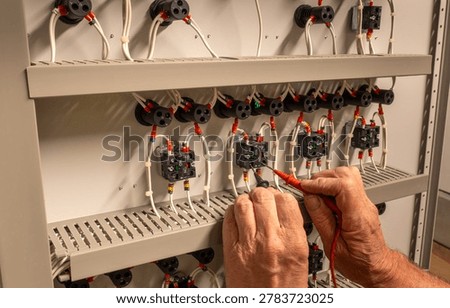 Electrical service engineer testing panel switches in an HVAC control cabinet. Electrician fault finding on air conditioning and ventilation control circuits.
