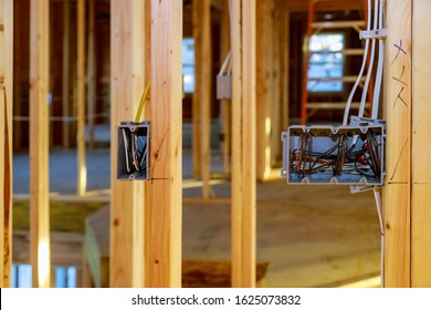 Electrical socket boxes with wires of wooden beams in a wall under construction unfinished frame