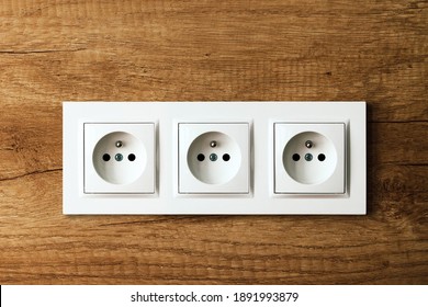 Electrical Socket Isolated On Wooden Kitchen Wall. Renovated Studio Apartment Power Supply Background. Empty Copy Space White Plastic Triple Power Outlet.