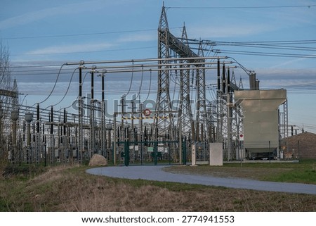 Electrical substation with complex high-voltage infrastructure, including transformers, transmission lines, and steel lattice structures.