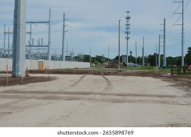 Electrical Substation Construction Site Featuring Power Lines and Equipment. Machinery and equipment. Utility poles, power lines, and soil preparation are visible, illustrating infrastructure developm