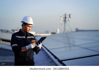 Electrical technician or professional engineer and tablet checking installation of solar roof panels on factory roof.