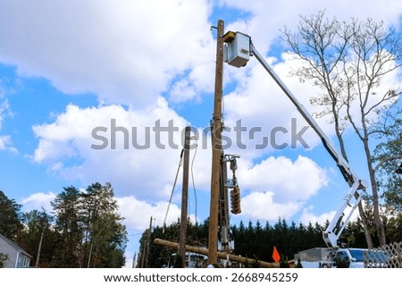 Electrical technician are using lifting platform to fix equipment on utility pole under works day