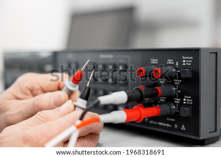 Electrical test leads in the hands of an electrician engineer. Working equipment of the specialist of the laboratory of metrology and standardization. Measuring instruments digital multimeter.