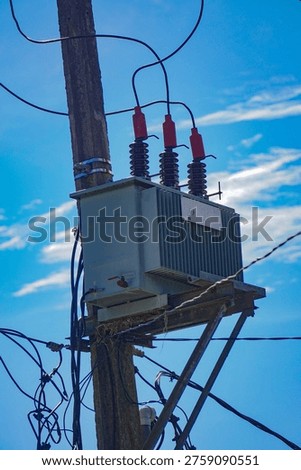 An electrical transformer mounted on a power pole with wires and insulators