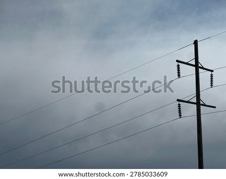 Electrical utility infrastructure with overhead power lines beneath gray cloudy sky in outdoor environment