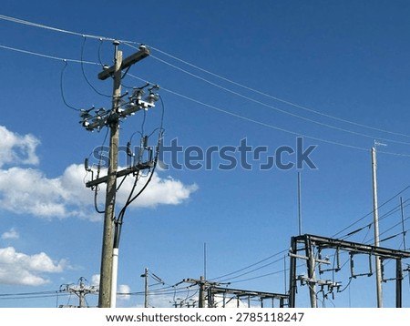 Electrical utility infrastructure and overhead power lines against clear blue sky showing public energy distribution network and outdoor utility systems