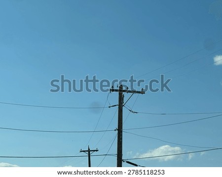 Electrical utility infrastructure and overhead power lines against clear blue sky showing public energy distribution network and outdoor utility systems