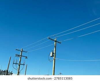Electrical utility infrastructure and power distribution lines against clear blue sky showing public energy network and outdoor utility systems