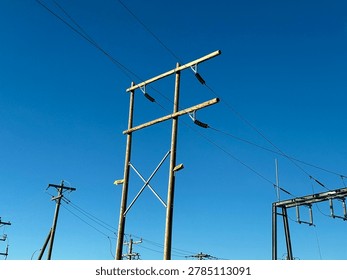 Electrical utility infrastructure and power distribution lines against clear blue sky showing public energy network and outdoor utility systems
