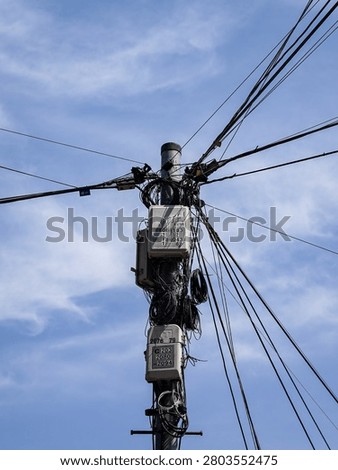 Electrical utility pole with numerous tangled wires and junction boxes.