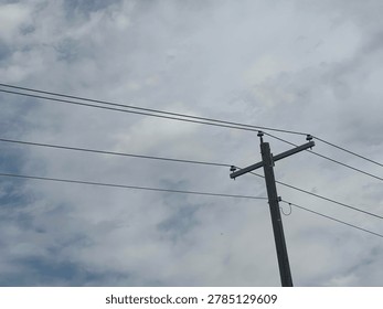 Electrical utility pole and overhead power lines against cloudy sky showing public infrastructure and energy distribution network