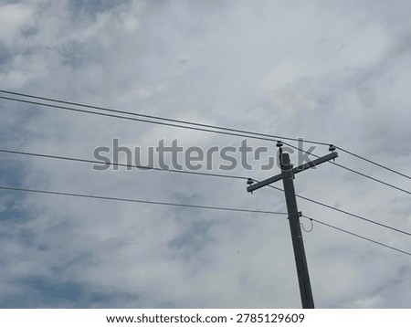 Electrical utility pole and overhead power lines against cloudy sky showing public infrastructure and energy distribution network