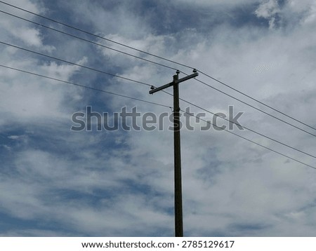 Electrical utility pole and overhead power lines against cloudy sky showing public infrastructure and energy distribution network