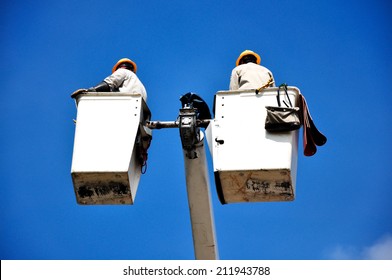 Electrical Utility Worker In A Bucket On Blue Sky Background