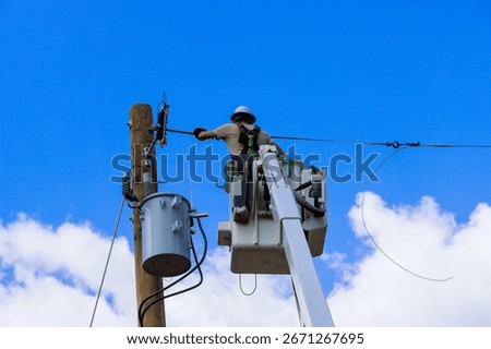 Electrical utility worker uses cherry picker to repair electrical lines on pole under work maintenance day