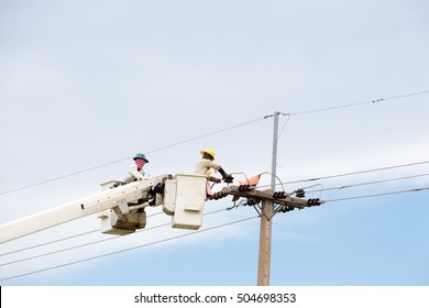 Electrical utility workers repairing problem with power line on the help of truck crane