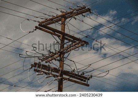 Electrical wires criss cross back and forth on a telephone pole.