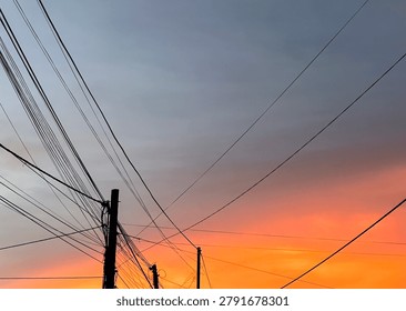Electrical wires crossing dramatic sunset sky with copy space