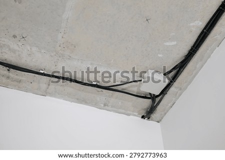 Electrical wiring and a junction box mounted on a concrete ceiling during construction or renovation work