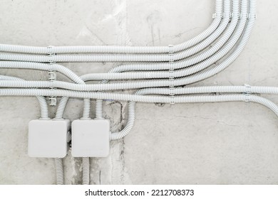 Electrical Wiring In A Protective Corrugation On The Wall. The Wires And Junction Box Are Installed On A Concrete Surface. Close-up