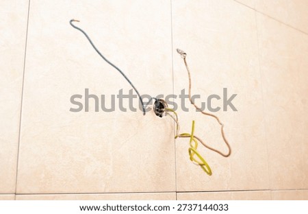 Electrical work in bathroom or kitchen showing colorful insulated wires prepared for light fixture or socket outlet installation.