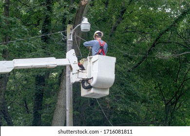 An Electrical Worker In A Bucket Truck Fixes Wires After A Storm Did Damage By Dropping A Tree Branch On The Lines